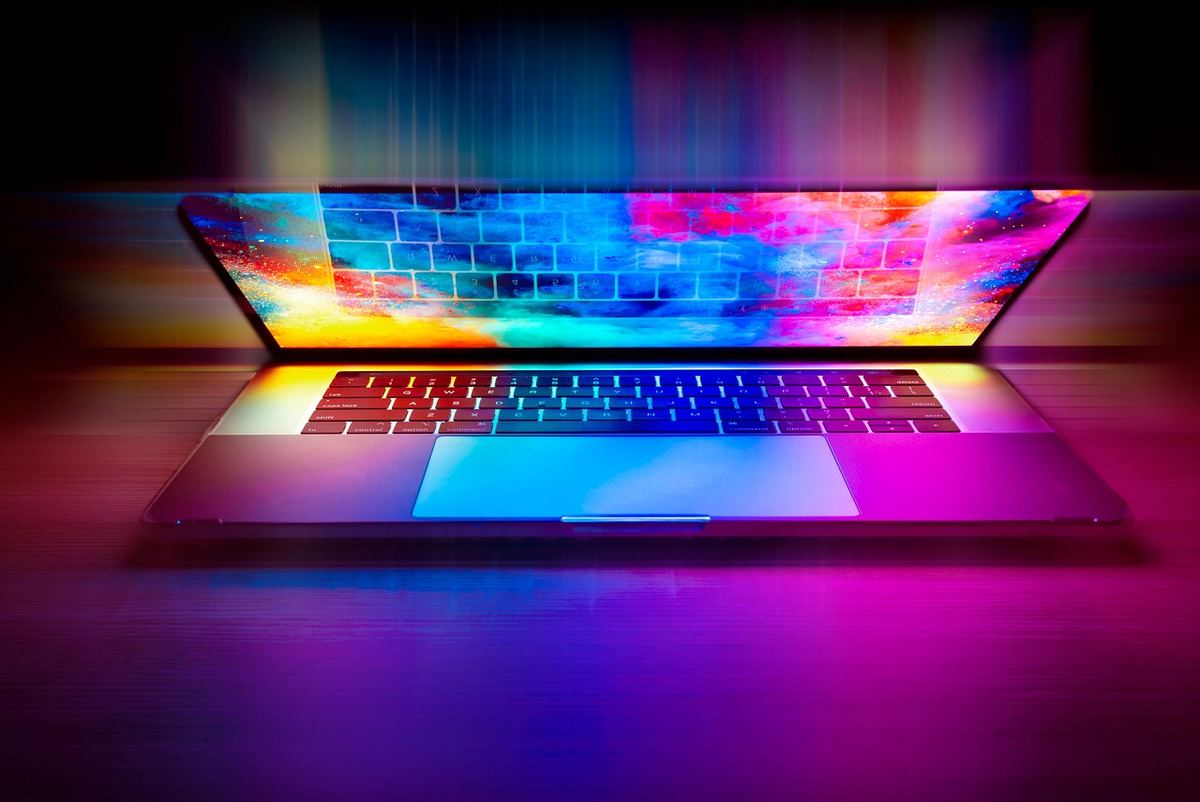 Laptop ouvert sur table, écran affichant un motif arc-en-ciel lumineux