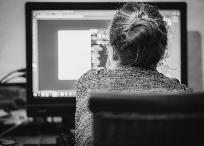 Une femme avec cheveux en chignon regarde l'écran d'ordinateur