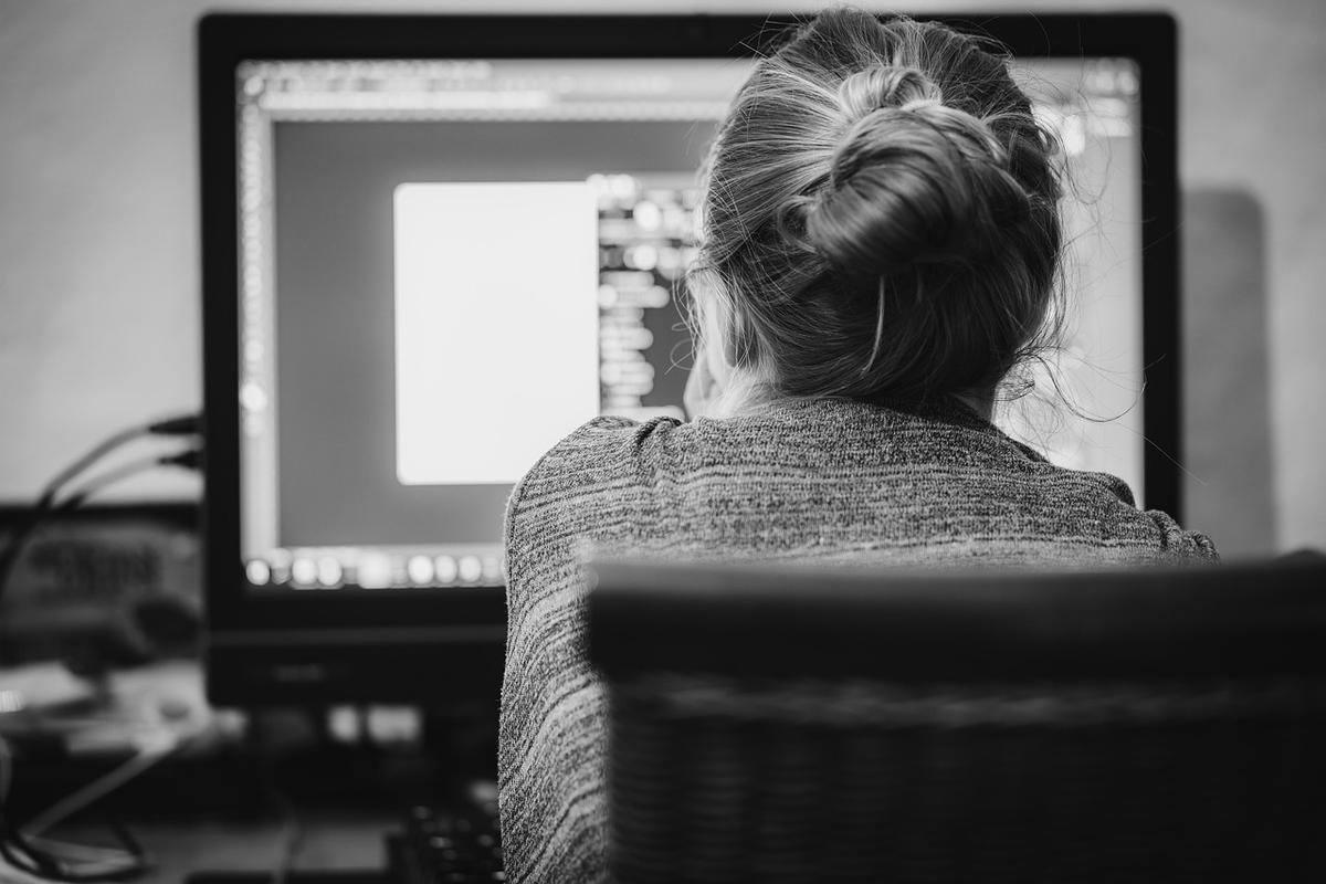Une femme avec cheveux en chignon regarde l'écran d'ordinateur