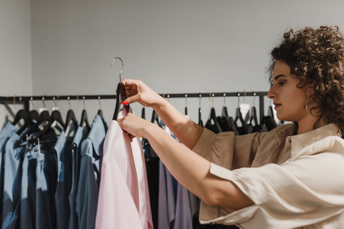 Femme sélectionne un vêtement sur une étagère dans un magasin