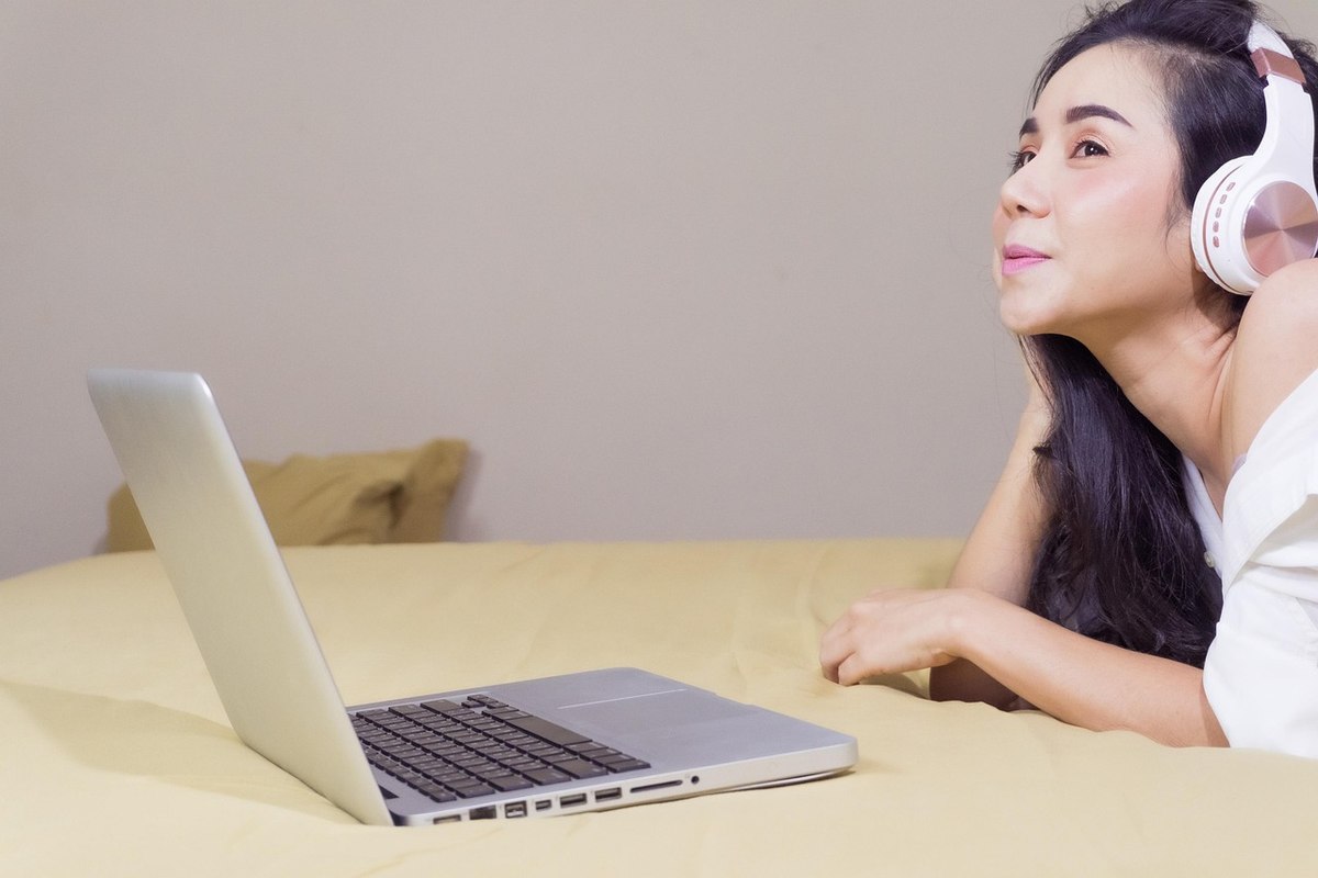 Une femme écoute de la musique via casque en utilisant un ordinateur portable