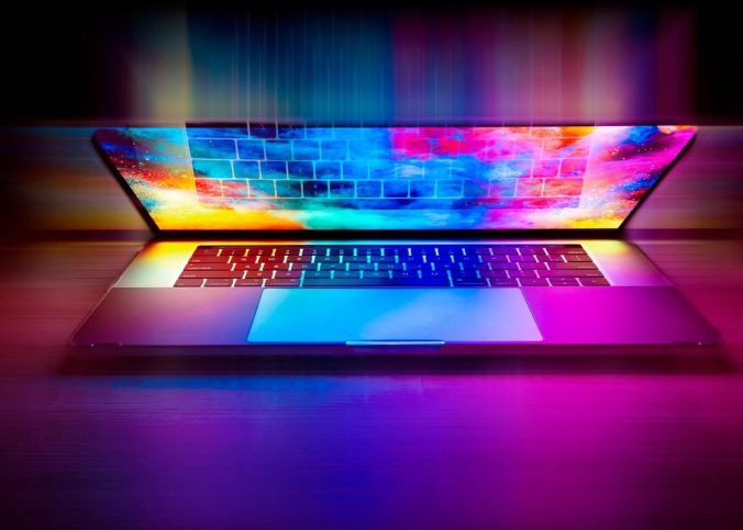 Un ordinateur portable illuminé par des néons multicolores sur fond sombre