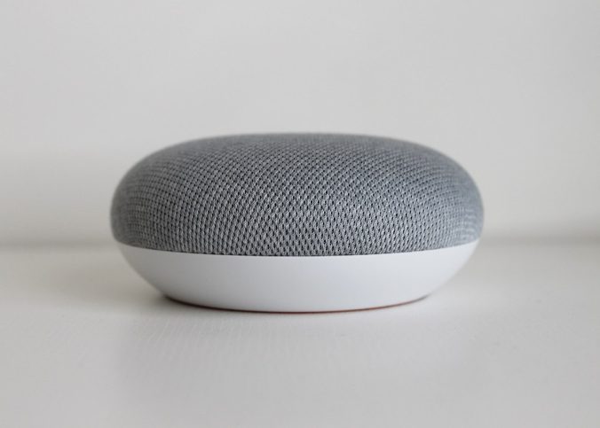 Un petit haut-parleur cylindrique gris et blanc sur fond blanc