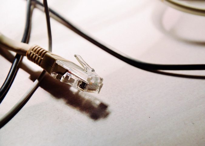 Un connecteur RJ45 et plusieurs câbles noirs sur une surface claire